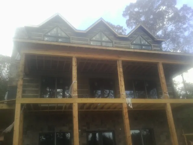 Dormers and porch framing on a large log home under construction — Roof Coating work by our crew in Blackstone