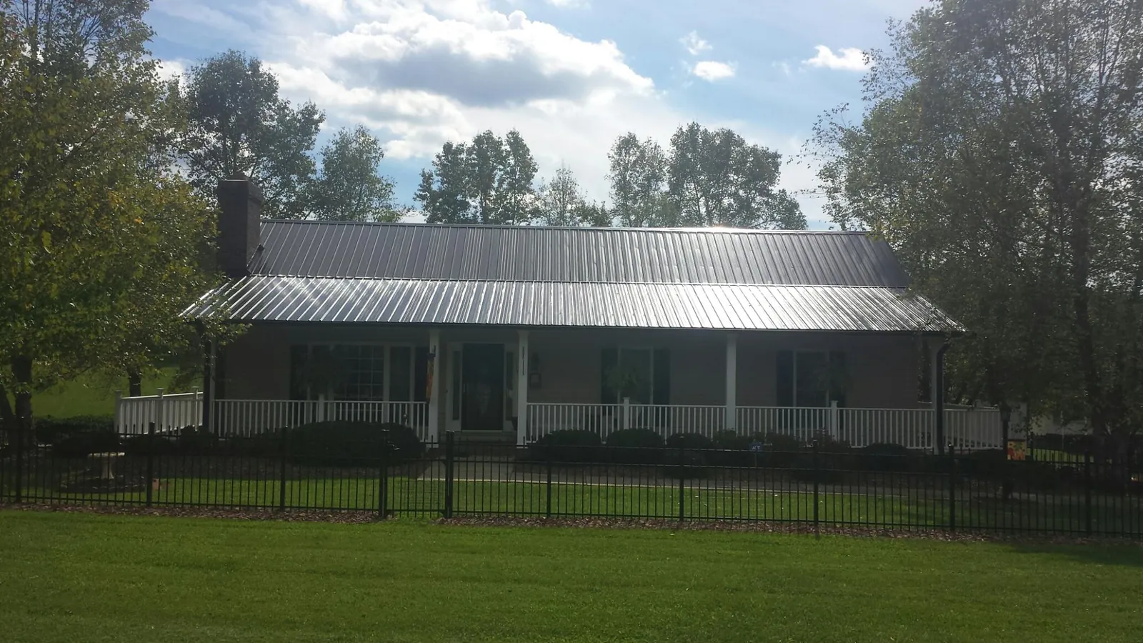 Gray metal roof on a brick ranch with a full width front porch — Gutter Guard Installation work by our crew in Blackstone